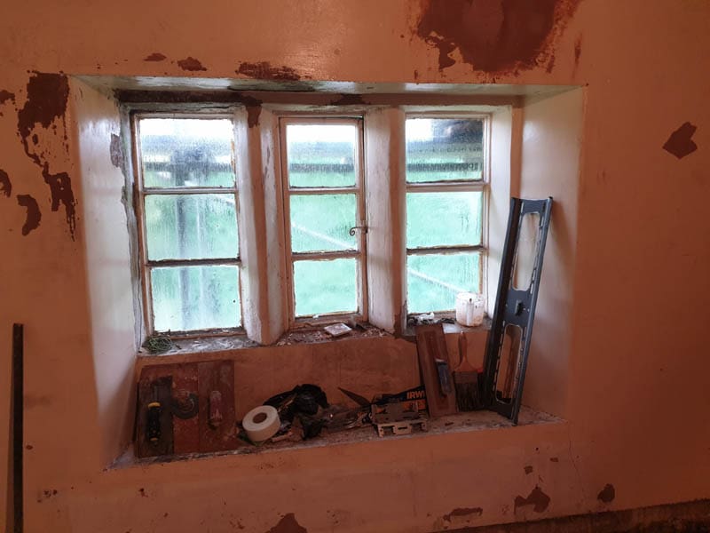 Internal view of the original timber casement windows in a listed property before replacement.