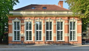 The image features a beautifully restored heritage building in Lithuania showcasing classic sash windows enhanced with LandVac vacuum glazing