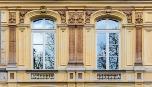 A historic building in Lithuania showcases elegantly restored windows framed by intricate ornamental woodwork The windows feature a combination of slim double glazing and advanced vacuum glazing The slim double glazing exhibits a subtle yet noticeable improvement